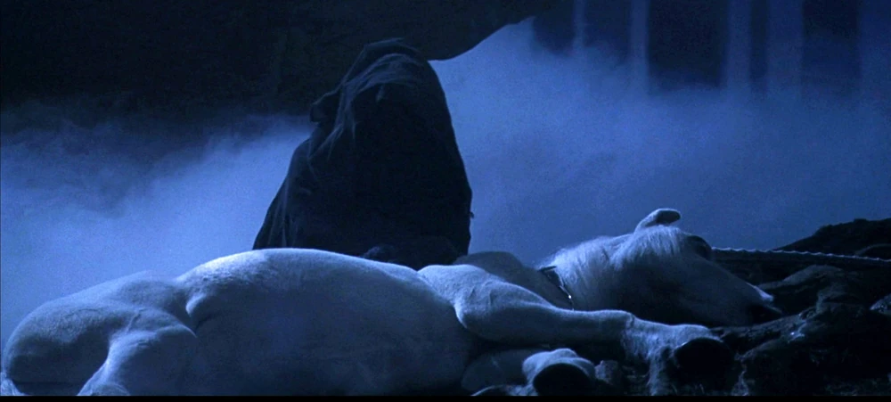 A cloaked dark figure bends over a fallen unicorn in a misty forest scene from Harry Potter, symbolizing Voldemort drinking unicorn blood.