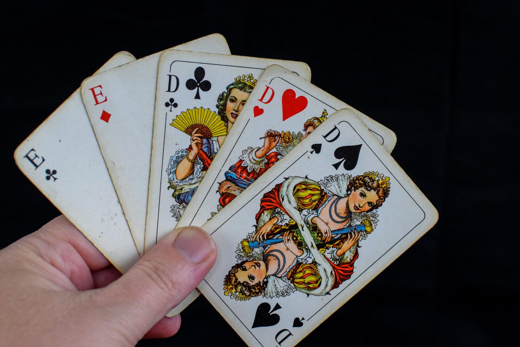 Hand holding playing cards, symbolizing the random cards we are dealt at birth and how each life begins with a different hand.